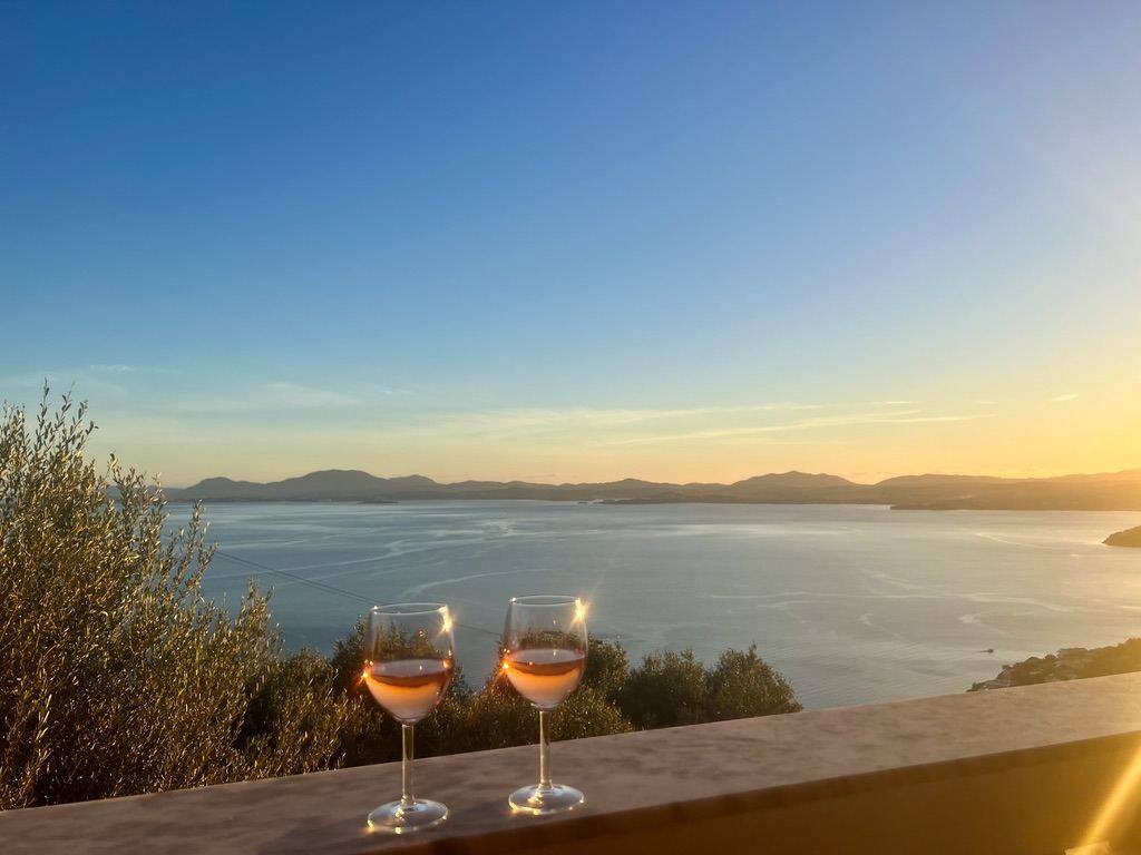 Two glasses of rosé on the wall at sunset over the bay