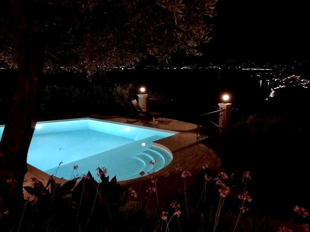 The pool lit at night with the coast lights beyond