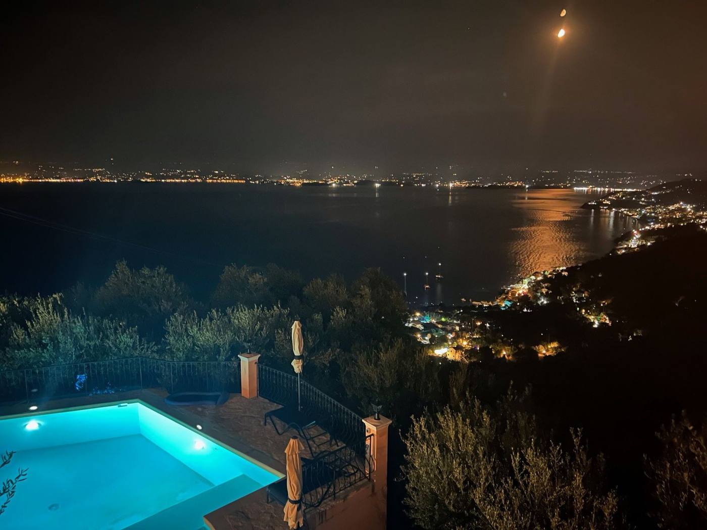 Night view over the lit pool to the lights of Corfu Town