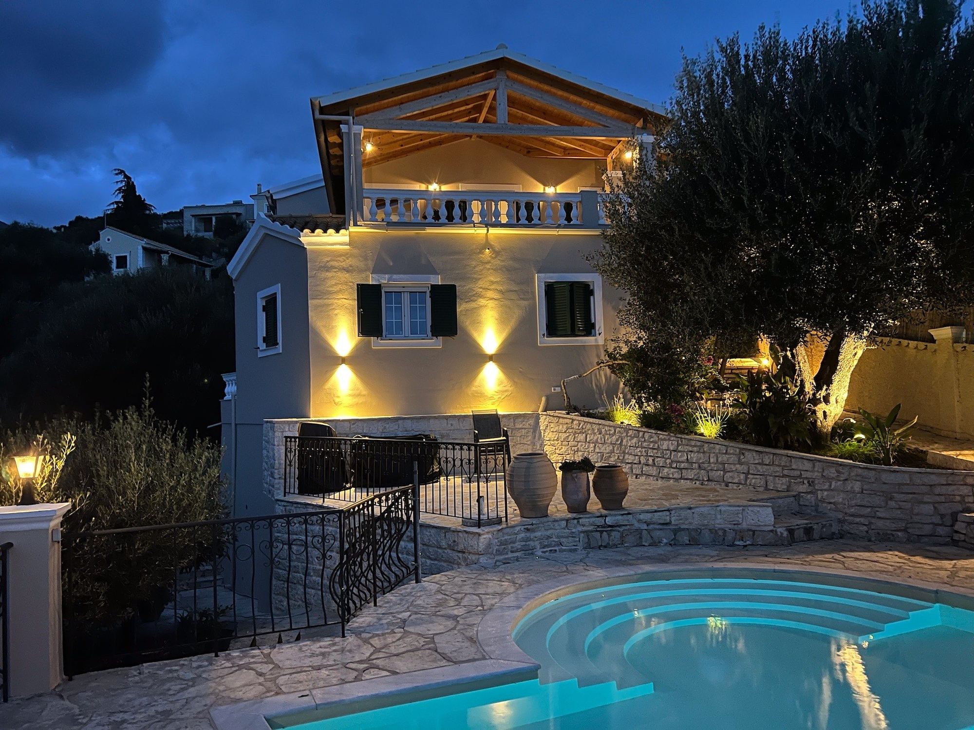 The villa lit up at dusk above its pool